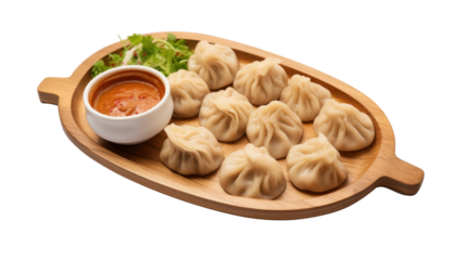 A wooden platter holds an array of cute dumplings, perfectly shaped and steaming. The dish is accompanied by a small bowl of spicy sauce and garnished with fresh herbs