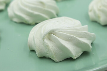 Light green apple marshmallows on a light green plate, close-up