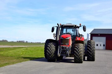 A big red tractor stands in the yard.