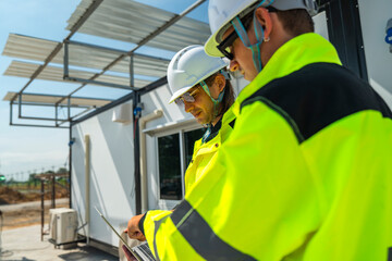 Two engineers in high visibility jackets discussing plans on a laptop at a modular construction...