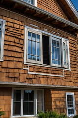 Fototapeta premium Rustic Wooden House Exterior with Vintage Windows and Shingle Facade. Classic Home Design, Real Estate, Property, Architecture