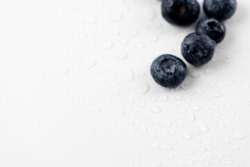 top shot close up on white photo background there are a lot of ripe big blueberries among drops of water healthy vitamins seasonal summer fruits vitamin C forest and bush berries