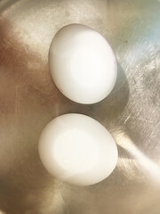 Boiling Eggs Two eggs boiling in a stainless steel pot with hot water. Steam rises as the eggs cook, creating a simple yet essential kitchen scene. A perfect representation of everyday cooking, meal