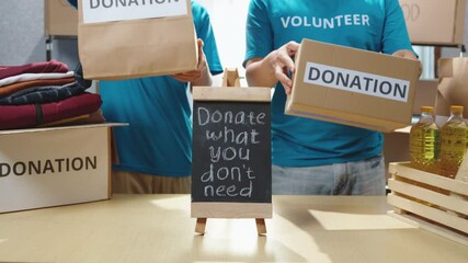 Volunteers showcasing donation boxes and food bags on a table at a charity center. A message board inspires the community to share and help those in need. Donation campaign, charity activity