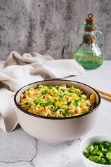 Instant noodles with corn and green onions in a bowl on the table vertical view
