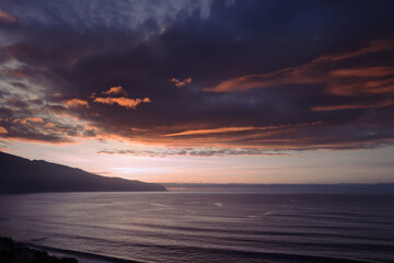 Landscape with dramatic clouds over the ocean, orange sunset