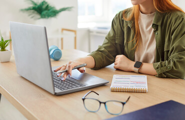 Close-up of a woman hands typing on a laptop at home. She is working or e-learning remotely as a...