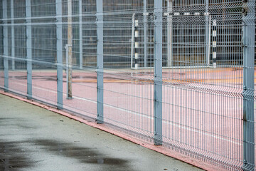 A fence with a red and white stripe is in front of a building