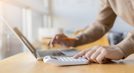 close up accountant employee man hand press on calculator to summarise or check about budget and profit of company annual in marketing department office room for business and financial concept