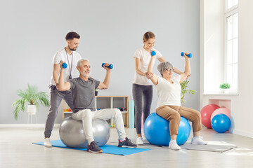 Obraz premium Young trainers at a rehabilitation center help an elderly couple to restore their muscles. An elderly couple receives medical care. Concept physiotherapy treatment, physical therapy