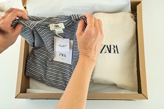 Alicante, Spain - January 30, 2025: Online shopping in Zara clothing store. Woman hands open cardboard box with new clothes and shoes. Zara is global fashion retailer of Inditex group