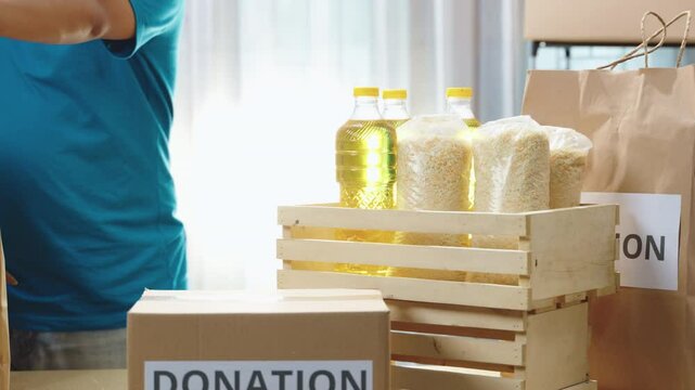 Donation boxes and essential food items prominently displayed on a table in a charity center. Encouraging community participation in social support activities. Charity work, food donation, social act