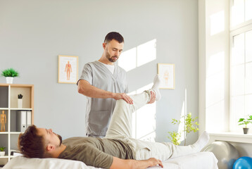 Physician or physiotherapist providing physical therapy and healing treatment for leg recovery to...