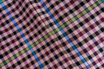 A detailed view of checkered fabric featuring pink, maroon, green, blue, and beige tones