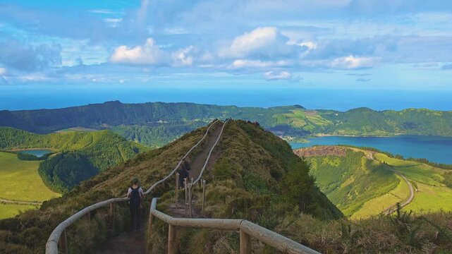 4K footage of a girl walking hiking trail to Miradouro da Grota do Inferno viewpoint in Sao Miguel Island, Portugal. Vertical video of Azores landscape panoramic view and Lagoa Azul