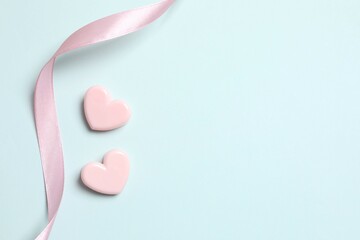 Beautiful pink hearts with silk ribbon on color background