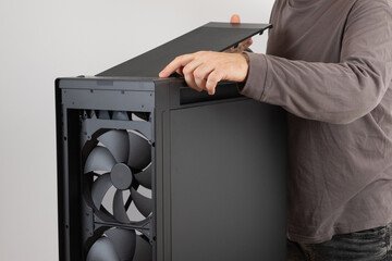 Man installing  top panel with dust filter from  PC case, empty big tower, chassis. Under top panel is place for 420 mm radiator for AIO cooling