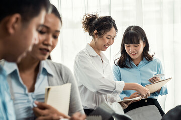 Asian office worker with smile working together in friendly corporate office environment. Group of happy business people in workplace with strong productive teamwork and sharing idea. Meticulous