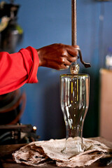 Hands, glassblower and man in workshop, product and process with craftsmanship. Closeup, person and employee in foundry, equipment and skills with vase, materials and manufacturing with industry
