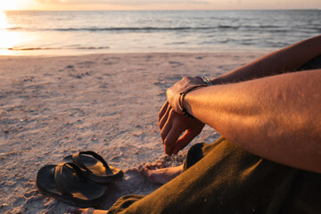 WOMAN IS SITTING ON THE BEACH AND ENJOYING THE SUNSET, HOLBOX, MEXICO