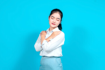 Young female student dressed in a uniform Standing With Hand on Heart Against Bright Blue Background
