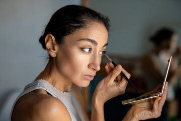 Woman Applying Eye Makeup with a Brush While Filming a Beauty Tutorial..