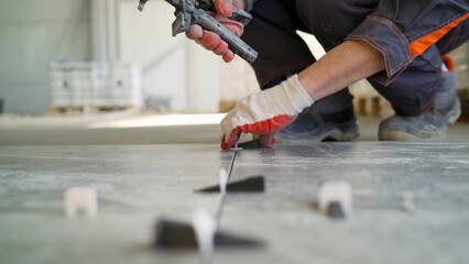 Tiler placing leveling wedges for tiles installation