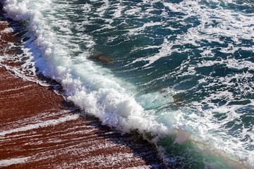 Vague sur une plage de sable ocre, avec tons plus vifs
