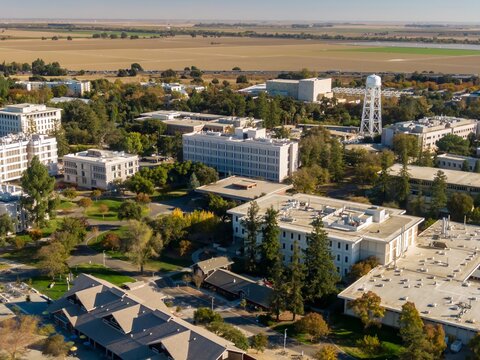 High-angle view of UC Davis campus, showcasing various buildings, trees, and open spaces. Agricultural fields are visible in the background, Davis, California, USA