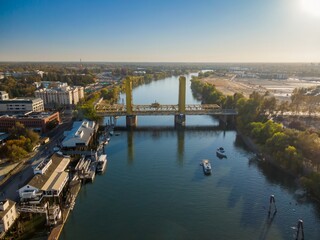 Obraz premium Aerial view of the Sacramento River, showing the iconic Gold Bridge, boats, and the city skyline. Beautiful day. Sacramento, Sacramento, California, USA