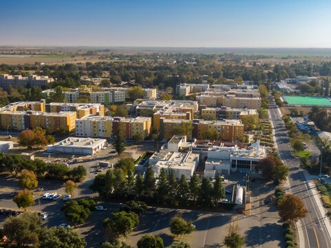 Aerial view of a UC Davis campus with apartment buildings, roads, and parking lots. Sunny day, showing urban sprawl.  Davis, California, USA
