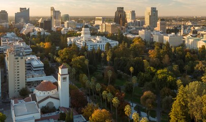 Aerial view of Sacramento, CA, showcasing the California State Capitol building amidst city parks and skyscrapers. Golden hour light bathes the cityscape. Downtown, Sacramento, California, USA