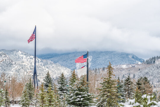 Avon Colorado ski mountain town city and American flags in winter snow late fall season with mountain peak and cloudy sky
