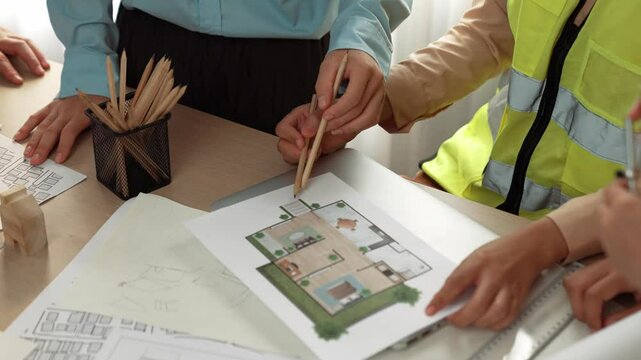 Smart architect and safety engineer discussion about building blueprint on table with architectural document, measurement tools and wooden block scatter around at modern office. Closeup. Delineation.