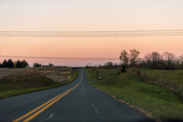 Obraz premium Virginia small rural countryside town village by agricultural winery farms on highway at sunset with winding road on rolling hills landscape