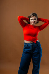 A fashionable young woman in a bold red top and wide-leg denim jeans strikes a dynamic and artistic...