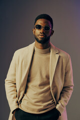 Obraz premium Stylish man in a beige coat and sunglasses, exuding confidence against a gradient background, showcasing modern fashion and urban elegance