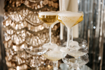 Champagne cascading in a tiered glass tower, golden bubbles overflowing.