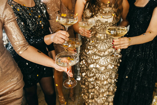 A glamorous celebration with elegantly dressed women toasting with champagne glasses, surrounded by gold confetti, exuding luxury and festive joy.