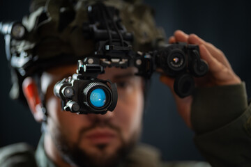 Military special forces soldier with night vision binocular mounted on helmet, close-up soft focus photo.