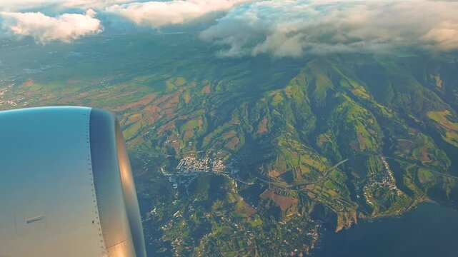 4K video footage of a flight over a tropical island in the middle of ocean from a plane window. Aerial view of Azores islands in Atlantic ocean from above