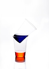 disposable glasses with colorful liquid one on top of another horizontal image