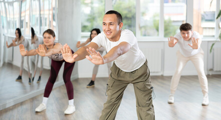 Young guy enjoys dancing, learning to twerk during group class at studio school for young people. Devotion of modern trend pastime, active lifestyle and hobbies