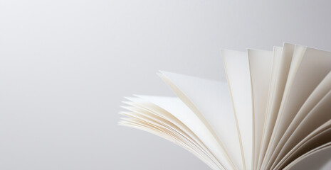 A close-up of white paper featuring three distinct creases on the left side, resembling pages of an open book or presentation material. The plain, neutral background and soft gray gradient highlight t