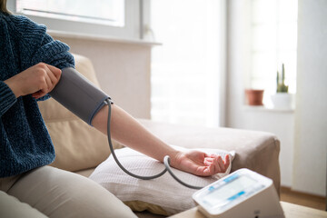 Young woman measuring blood pressure at home close up