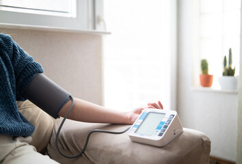 Young woman measuring blood pressure at home close up