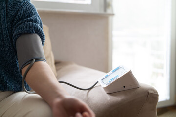 Young woman measuring blood pressure at home close up