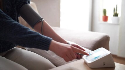Young woman measuring blood pressure at home close up