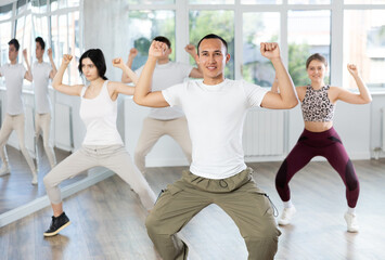 Fototapeta premium Group of young men and women rehearsing jazz funk dance in studio