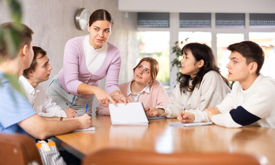 Young female tutor teaching group of students in college
